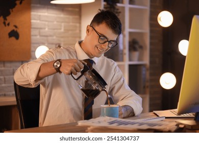 Young businessman pouring coffee in office at night - Powered by Shutterstock