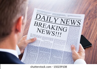 Young Businessman Reading Breaking News On Newspaper