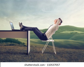 Young businessman relaxing at his desk in the middle of a green meadow - Powered by Shutterstock