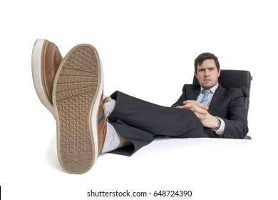 Young businessman is relaxing at workplace and has his feet on desk. Isolated on white background.