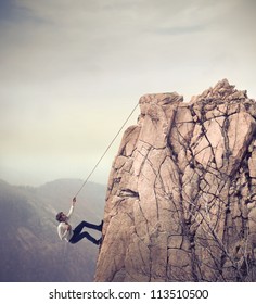 Young businessman scaling a rock