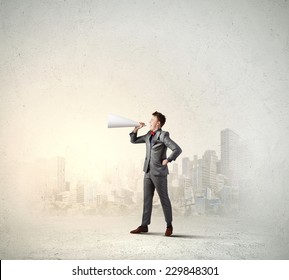 Young businessman screaming emotionally in paper trumpet - Shutterstock ID 229848301