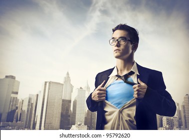 Young businessman showing the superhero suit under his shirt with cityscape in the background