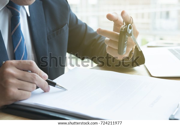 young businessman sign sales contract with car
key at office. ownership, customer buying and salesman selling
transportation concept.