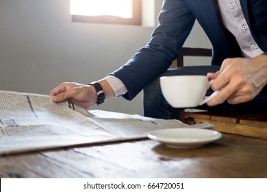 Young businessman sitting in a cafe drinking coffee and reading newspaper. - Powered by Shutterstock