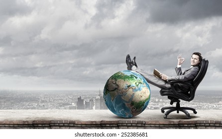 Young businessman sitting in chair with book in hands. Elements of this image are furnished by NASA - Powered by Shutterstock