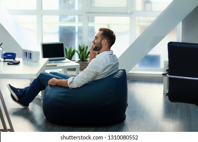 Young Businessman Sitting On Beanbag Chair In Office