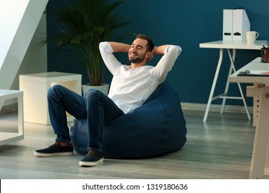 Young Businessman Sitting On Beanbag Chair In Office