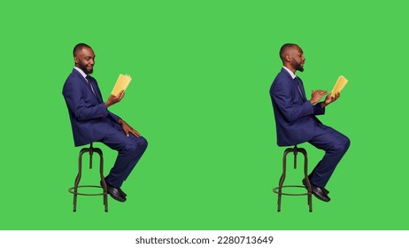 Young businessman sitting on chair reading story book or novel, being focused on fictional tale for leisure activity. Confident entrepreneur reading literature over full body green screen. - Powered by Shutterstock