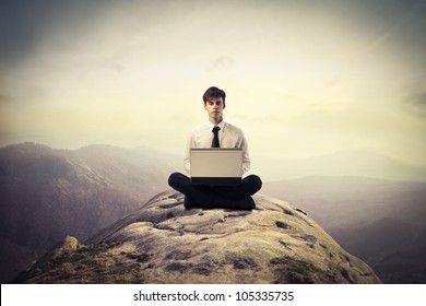 Junge Geschäftsleute, die auf einem Hügel sitzen und einen Laptop benutzen