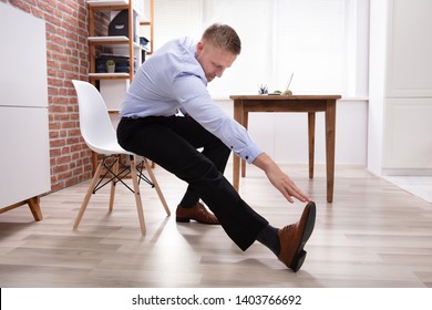 Young Businessman Sitting On White Chair Starching His Body At Work Place