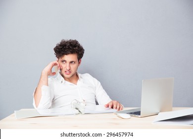 Young businessman sitting at the table with laptop and talking on the phone - Shutterstock ID 296457974