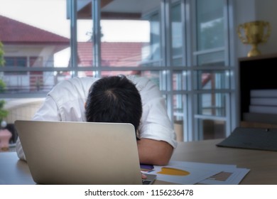 Young Businessman Sleeping And Overworked Near Laptop At Office.He Is 20-30 Years Old In White Shirt And Black Plant.Copy Space And Dark Light.