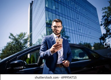 Young Businessman Standing Near The Car And Holding Phone