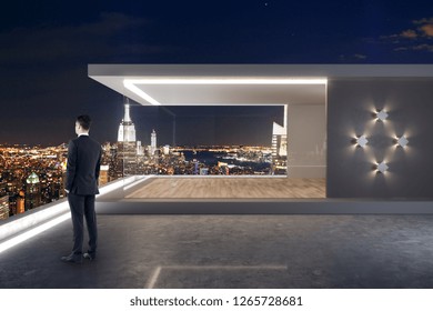 Young Businessman Standing On Modern Rooftop With Penthouse And Night New York City View