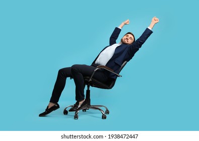 Young Businessman Stretching In Comfortable Office Chair On Turquoise Background