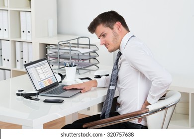 Young Businessman Suffering From Backpain While Working On Laptop In Office