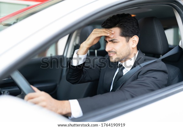 Young businessman suffering from headache while\
driving car in city