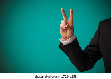 Young businessman in suit showing hand with two fingers up over green background.  - Powered by Shutterstock