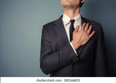 Young businessman is swearing allegiance with his hand on his chest