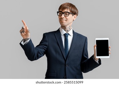 Young businessman with tablet computer using virtual screen on grey background