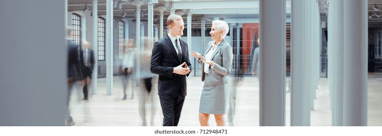 Young businessman talking with boss in industrial interior, panorama
