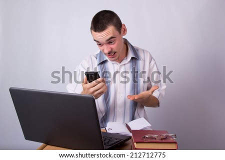 Young businessman is talking on a smartphone, at the workplace in the office. Emotions perturbations, complex conversation