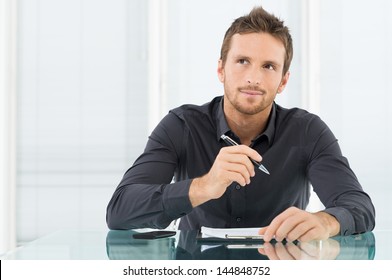 Young Businessman Thinking And Wondering While Writing A Paper