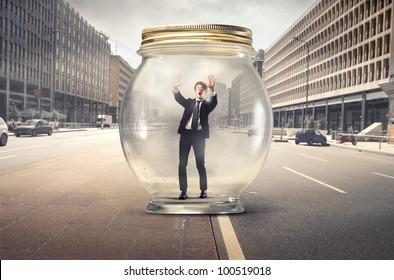 Young Businessman Trapped In A Glass Jar In The Middle Of A City Street