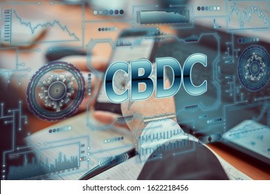 A young businessman uses a futuristic smartphone with the latest holographic technology of augmented reality with the inscription "CBDC". Central bank digital currency concept - Powered by Shutterstock