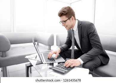 Young Businessman Using Calculator And Laptop