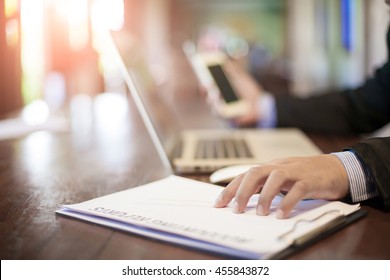 Young businessman using his laptop, cellphone, stock chart , close up