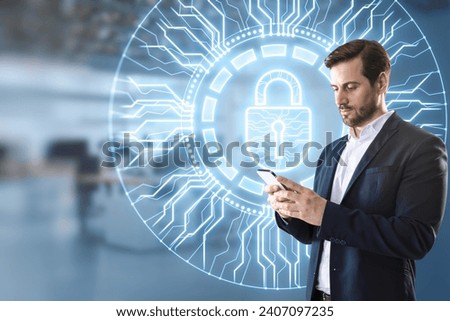 Young businessman using mobile phone with creative glowing round padlock hologram with circuit on blurry office interior background. Secure, web protection and antivirus concept