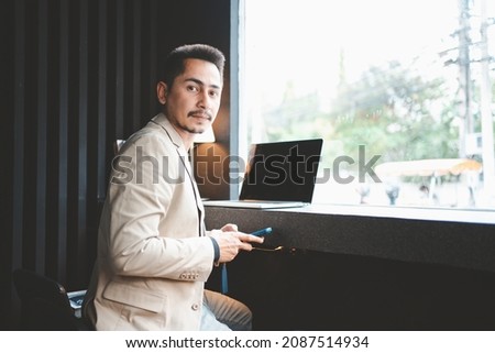 Young businessman using phone while working in cafe.