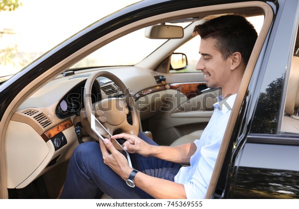 Young businessman using\
tablet in car