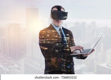 Young businessman in VR headset holding laptop