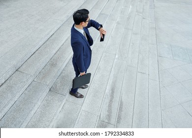 Young businessman waiting for colleague outdoors and checking time on smartwatch - Powered by Shutterstock