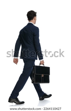 young businessman walking and holding a briefcase, wearing a suit and tie against white background