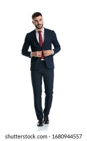 Young Businessman Wearing Navy Suit Walking While Opening His Jacket And Looking Away Serious On White Studio Background