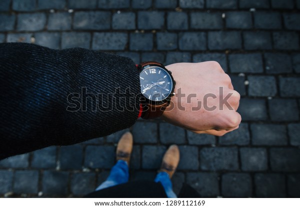Young businessman\
wearing watch with coat. Winter in the city. Lifestyle photo. Urban\
scene in the Prague. 
