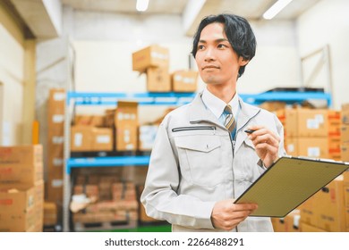 Young businessman in work clothes managing inventory in a warehouse - Powered by Shutterstock