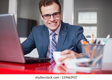 Young businessman working in bright office, sitting at desk with laptop. - Shutterstock ID 159463937
