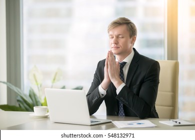 Young Businessman Working At Desk In Yoga Pose, Praying, Meditating, Relaxing. Stress Free Work, Time For Practice, Mindfulness And Wellbeing, Stay Healthy On Physical, Mental Emotional Level Concept