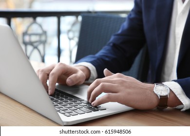 Young Businessman Working With Laptop In Outdoor Cafe, Closeup