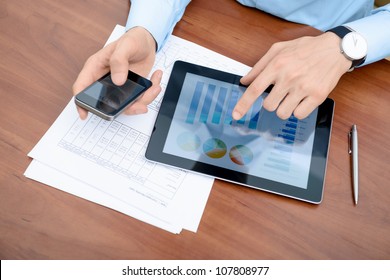Jovem empresário que trabalha com dispositivos modernos, tablet digital e telefone celular.