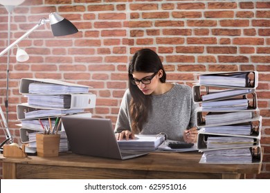 Young Businessman Working At Office With Stack Of Folders On Desk
