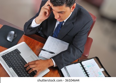 young businessman working on a laptop and speaking on mobile phone - Shutterstock ID 36104644
