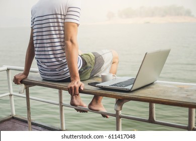 Young Businessman working remotely on the Beach.  Businessman working with computer on the beach.
