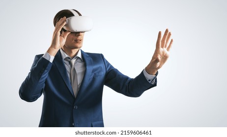 Young Businessman Working In Virtual Reality Office In VR Glasses, Presses His Hand Virtual Interface On Abstract Light Grey Backdrop. Innovate And Future Technology Concept, Close Up