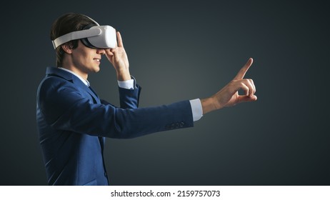 Young Businessman Working In Virtual Reality Office In VR Glasses, Presses His Finger Virtual Interface On Abstract Black Backdrop. Innovate And Future Technology Concept, Close Up